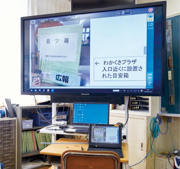 写真：電子黒板とPC、タブレットを連携させて授業で活用。他にも実物投影機を用いて教科書や児童のノートを映すなど効率的な授業が行われている